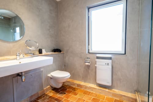 Salle de bain moderne à la villa La Girelle à Honfleur avec lavabo blanc, toilettes murales, sèche-serviettes chauffant et carrelage terre cuite