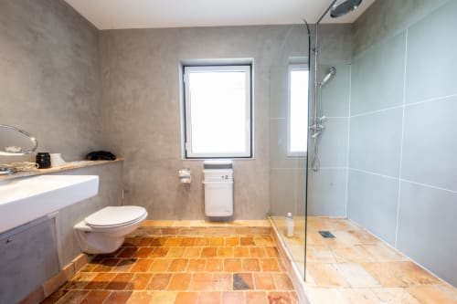 Salle de bain moderne avec carrelage en terre cuite, douche à effet pluie et robinetterie murale à la villa La Girelle à Honfleur