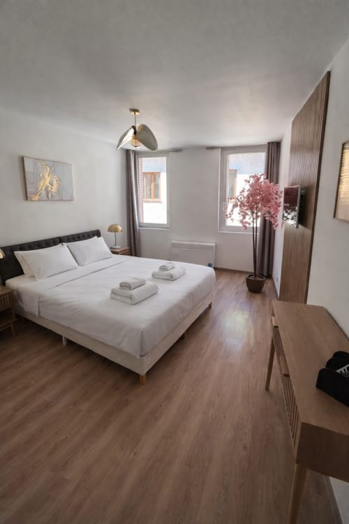 Chambre moderne de l'hôtel Le Clos Androne à Sisteron avec lit queen, décor minimaliste et vue sur jardin