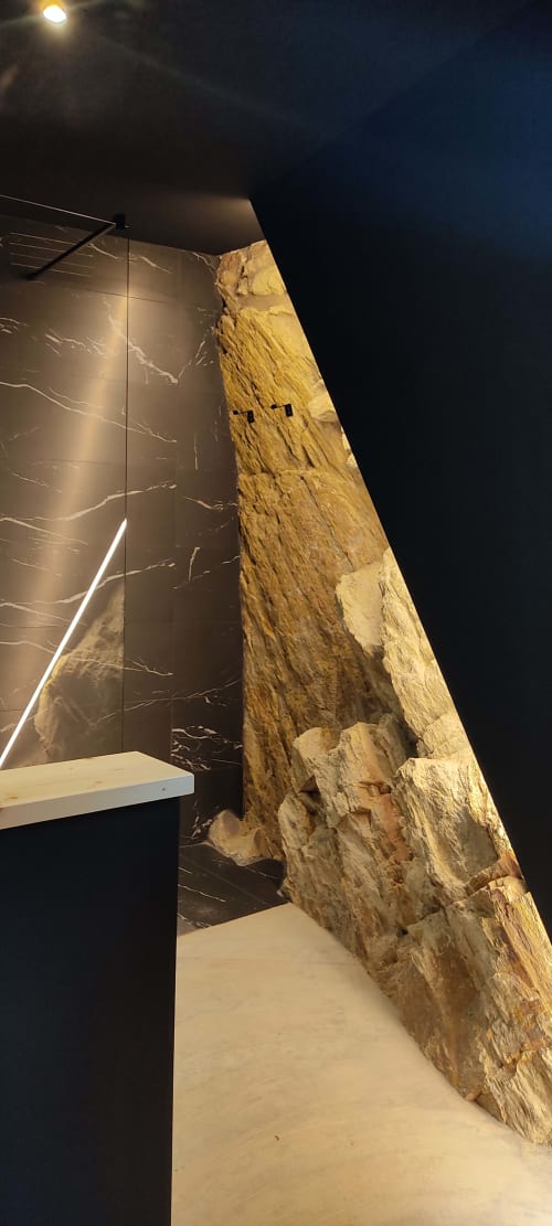Baño con paredes de piedra, rocas rústicas expuestas y accesorios modernos en la casa rural Hotel Mas D'En Roqueta