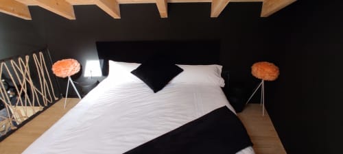 Moderna habitación del Hotel Mas D'En Roqueta con ropa de cama blanca, cabecero negro, vigas de madera y flores naranjas decorativas