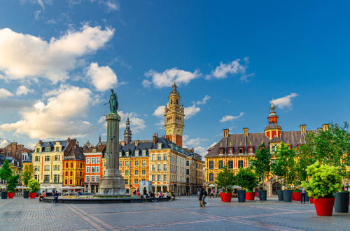 La Grand Place de Lille en France avec ses bâtiments historiques colorés, une statue et des tours sous un ciel bleu