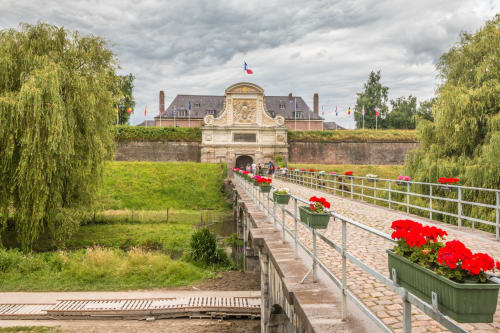 Entrée fortifiée avec pont-levis et géraniums rouges à la Ferme de la Forterie à Verlinghem, France