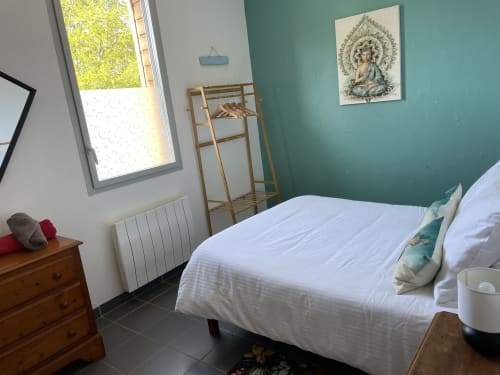 Chambre lumineuse aux Prairies du Val d'Amboise avec lit blanc, mur accent bleu-vert, mobilier en bois et lumière naturelle