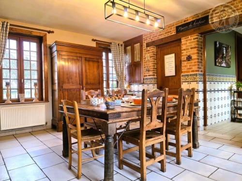 Salle à manger rustique à la Ferme de la Forterie avec table en bois, murs en pierre et mobilier d'époque à Verlinghem