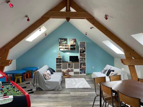 Spacieuse salle de jeux mansardée aux Prairies du Val d'Amboise avec mur d'accent turquoise, lits, rangements et jeux.