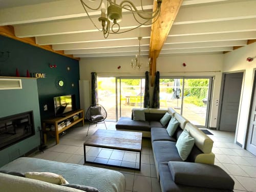 Spacieux séjour aux Prairies du Val d'Amboise avec vue sur la terrasse, canapé, cheminée et poutres apparentes à Noizay