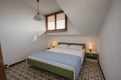 Bright attic bedroom at Anthea hotel in Lignano Sabbiadoro with green bed frame, skylight window, and patterned tile floor