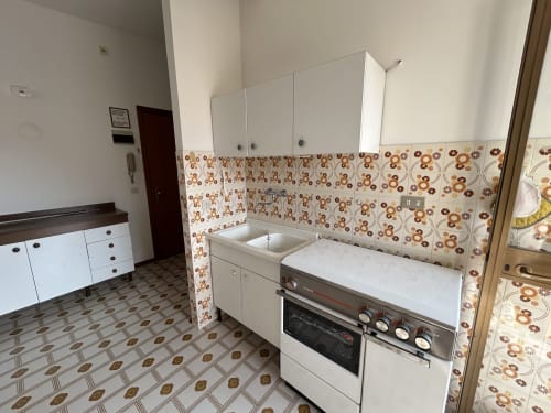 Villa Loris kitchen at Anthea Hotel, Lignano Sabbiadoro, with vintage floral tile backsplash and white cabinetry