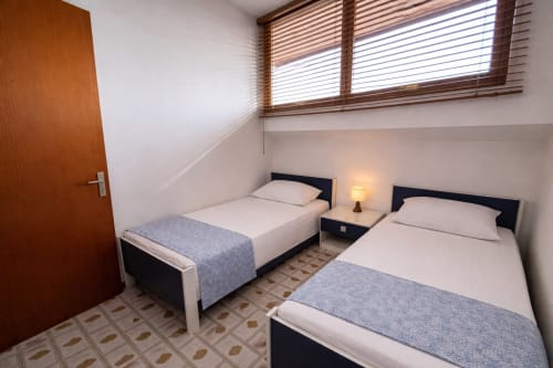 Twin bedroom at Anthea Hotel, Lignano Sabbiadoro with two single beds, bedside lamp, and wooden window blinds