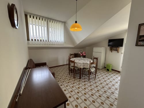 Villa Loris 2 dining area with round table, chairs, and yellow pendant light in Lignano Sabbiadoro