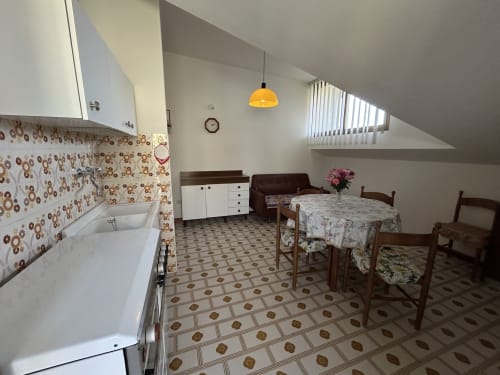 Villa Loris 2 room at Anthea hotel in Lignano Sabbiadoro with kitchenette, dining area, and bedroom under sloped ceiling