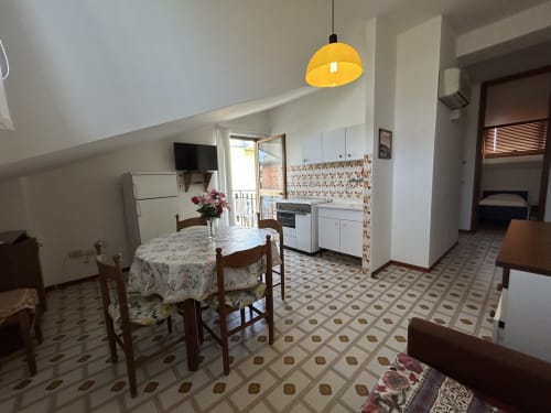 Villa Loris 2 kitchen-dining area at Anthea Hotel, Lignano Sabbiadoro, with yellow pendant light and garden view