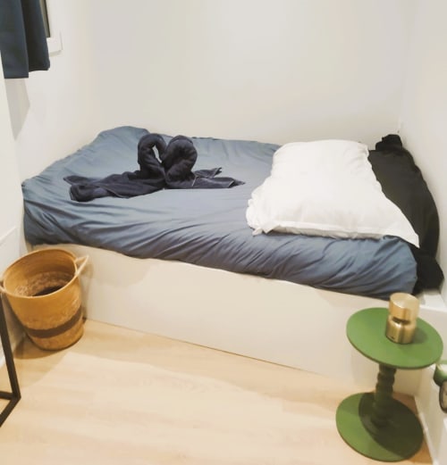 Cozy Paris apartment bedroom at Conciergerie Saint Martin with blue bedding, white pillow, and green side tables