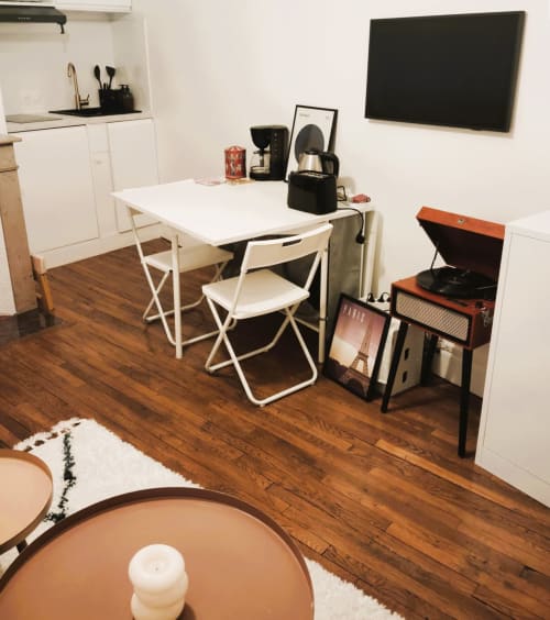 Cozy Paris apartment studio with white dining table, cream chairs, record player, and flat-screen TV in living area
