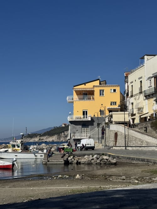 Luminoso appartamento giallo con vista su Marina Grande a Sorrento, con barche da pesca e mare blu