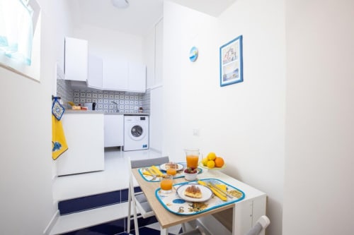 Cucina dell'appartamento Sealand Lobra a Sorrento con tavolo colazione apparecchiato con limoni, succhi e decorazioni nautiche
