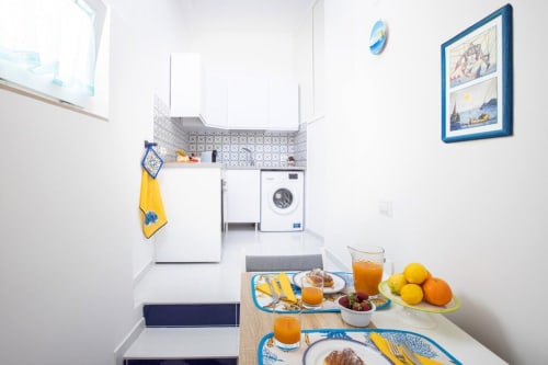 Cucina dell'appartamento Sealand Lobra a Sorrento con colazione allestita, arredamento tematico blu e giallo