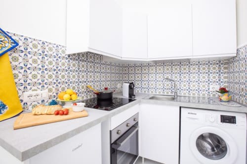 Cucina moderna di Appartamenti Momi Sorrento con piastrelle blu, mobili bianchi e lavatrice