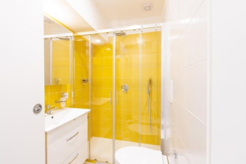 Bagno moderno dell'appartamento Sealand Lobra a Sorrento con piastrelle gialle, box doccia in vetro e lavabo bianco