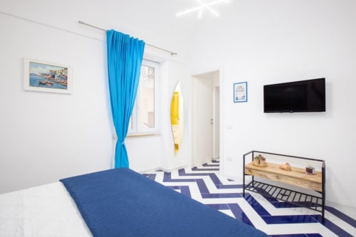 Camera da letto Sealand Lobra a Sorrento con biancheria blu, tende luminose e arredi nautici presso Appartamenti Momi
