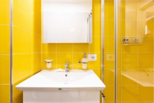 Bagno luminoso giallo brillante con lavabo e specchio bianchi negli Appartamenti Momi, Sorrento