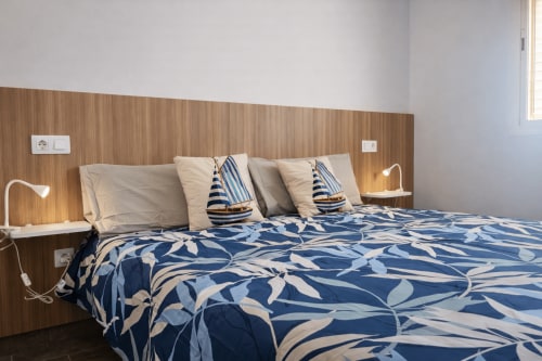 Beachfront apartment bedroom with nautical-themed bedding, wooden headboard, and sailboat pillows at La Aldea vacation rental