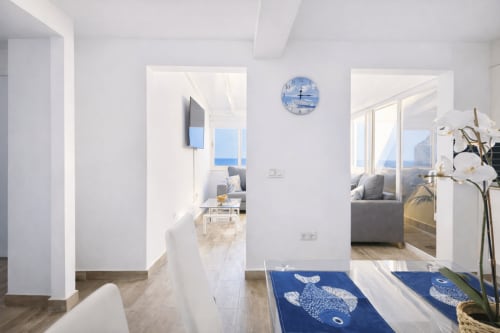 Modern coastal apartment with sea view, bright living room featuring blue nautical decor, white walls, and ocean-facing