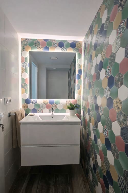 Modern bathroom with colorful hexagonal tiles, white vanity, and illuminated mirror at La Aldea apartment