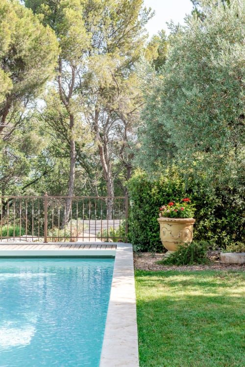 Piscine du Mas Carré aux eaux turquoise, terrasse en bois, garde-fou métallique et arbres méditerranéens luxuriants à Séguret, France