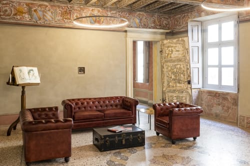 Elegante lounge del Palazzo Fauzone Relais & Spa con sedute Chesterfield bordeaux, affreschi al soffitto ornati e terracotta