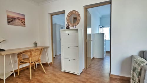Modern apartment in La Aldea with wooden desk, wicker chair, white storage cabinet, and city views
