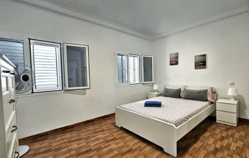 Bright bedroom in Apartamento Galoponte, La Aldea with white bed, wooden floor, windows, and city view