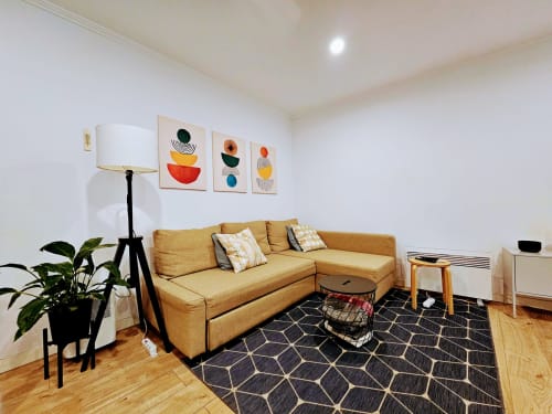 Sala de estar moderna no Lisbon Village Apartments com sofá seccional dourado, arte abstrata na parede, tapete geométrico e madeira