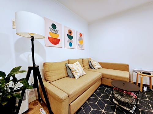 Sala de estar aconchegante no Lisbon Village Apartments com sofá mostarda, luminária moderna, arte abstrata colorida e elementos de madeira