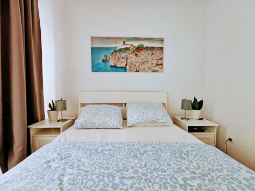 Quarto aconchegante em Martim Moniz Charming, Lisboa com roupa de cama estampada azul, móveis de madeira e arte costeira acima da cama