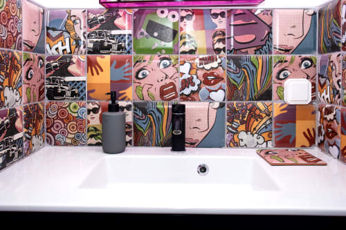 Colorful pop art bathroom backsplash with white sink, gray soap dispenser, and black faucet at Locavilla villa in Colombes