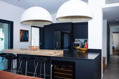 Modern villa kitchen at Locavilla with black cabinetry, island seating, and dome pendant lights