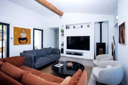 Modern living room at Locavilla villa in Colombes with terracotta and navy sofas, flat-screen TV, and wooden beam ceiling