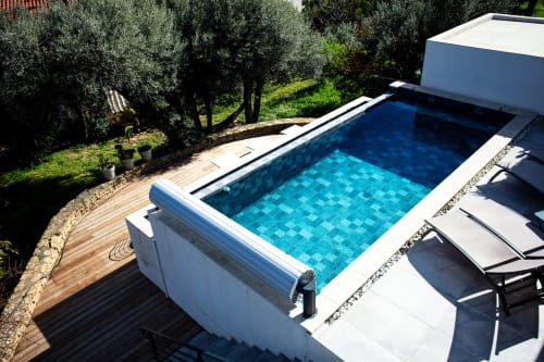 Modern swimming pool with blue tile pattern at Villa Granières, Locavilla hotel in Colombes, surrounded by olive trees and