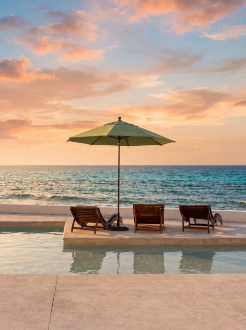 Sunset beach view with lounge chairs and umbrella at Malkita Sol oceanfront property in Highland Mills