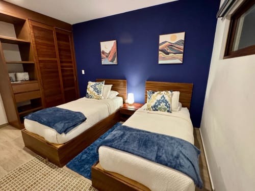Twin beds with navy blankets in modern bedroom with deep blue walls at Malkita Homes, Highland Mills