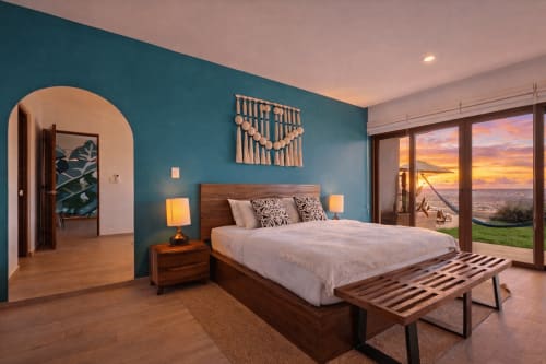 Modern oceanview master bedroom at Malkita Sol in Highland Mills with teal walls, wooden bed, sunset sea views through glass