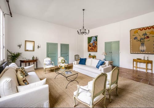 Élégant salon provençal à la Conciergerie Maurin, Arles avec canapés blancs, portes vertes et vue sur le jardin