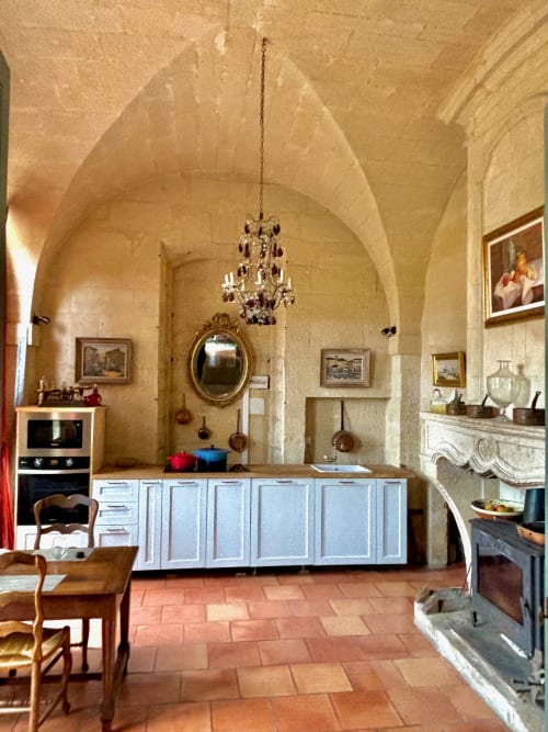 Élégante cuisine voûtée dans villa provençale d'Arles avec cabinetry blanc, lustre et sols en terre cuite
