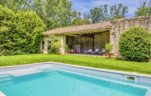 Somptueuse piscine aux eaux turquoise surplombant une maison en pierre avec terrasse couverte en Arles, Provence