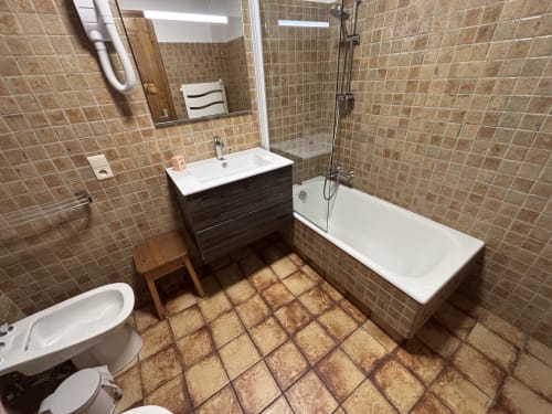 Modern bathroom in Studio Aravis at Chez Francine with vanity, bathtub, toilet, and beige tile flooring