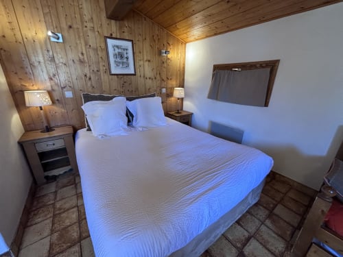 Studio Aravis bedroom at Chez Francine in Notre Dame de Bellecombe, featuring wooden walls, queen bed with white linens, and