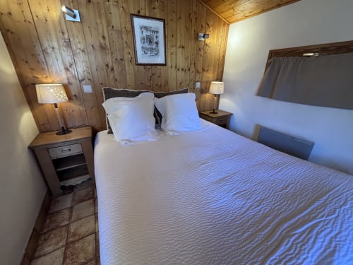 Studio Aravis bedroom at Chez Francine in Notre Dame de Bellecombe with wood-paneled walls, queen bed, and bedside lamps