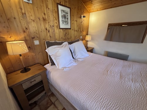 Cozy wood-paneled bedroom at Chez Francine's Studio Aravis in Notre Dame de Bellecombe with queen bed, warm lighting, and